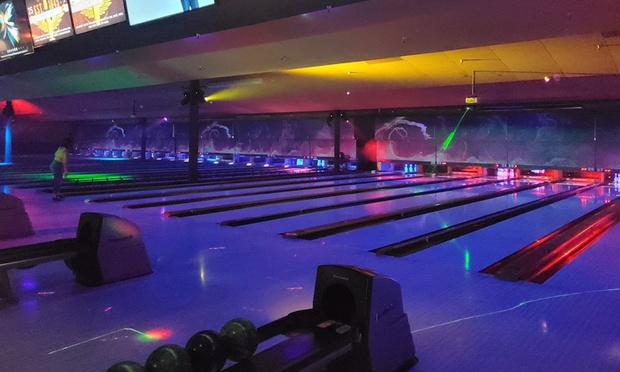 People bowling on modern lanes with colorful lights at All Star Lanes.