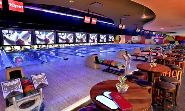 A modern bowling alley with a large video screen and lounge seating.