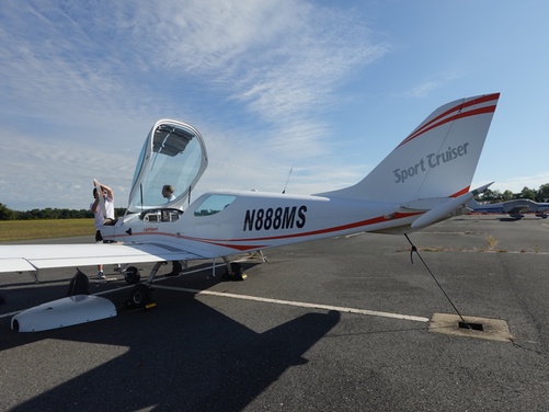 A person in the cockpit of a small plane with an instructor, flying over a landscape.