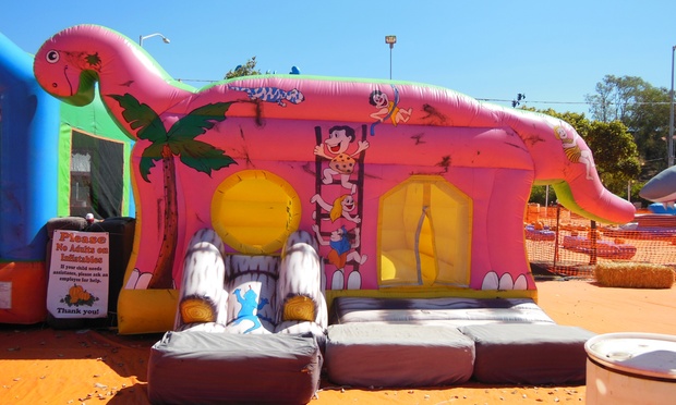 Children playing on large, colorful outdoor inflatables and water slides.