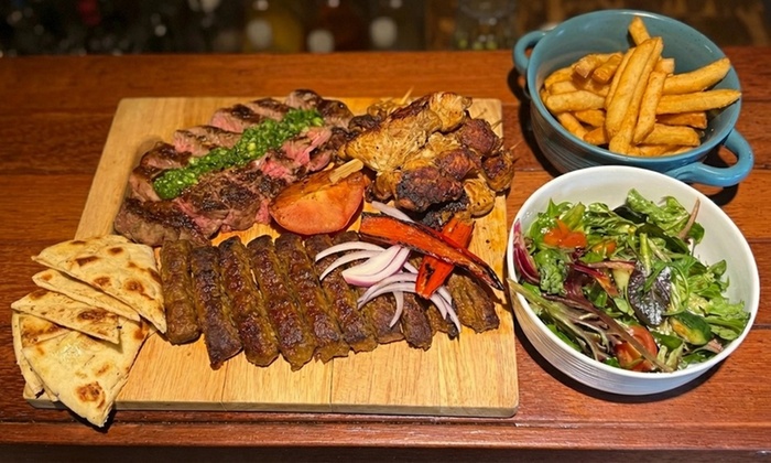 A sizzling flame-grilled steak with vegetables and sauce on a plate.