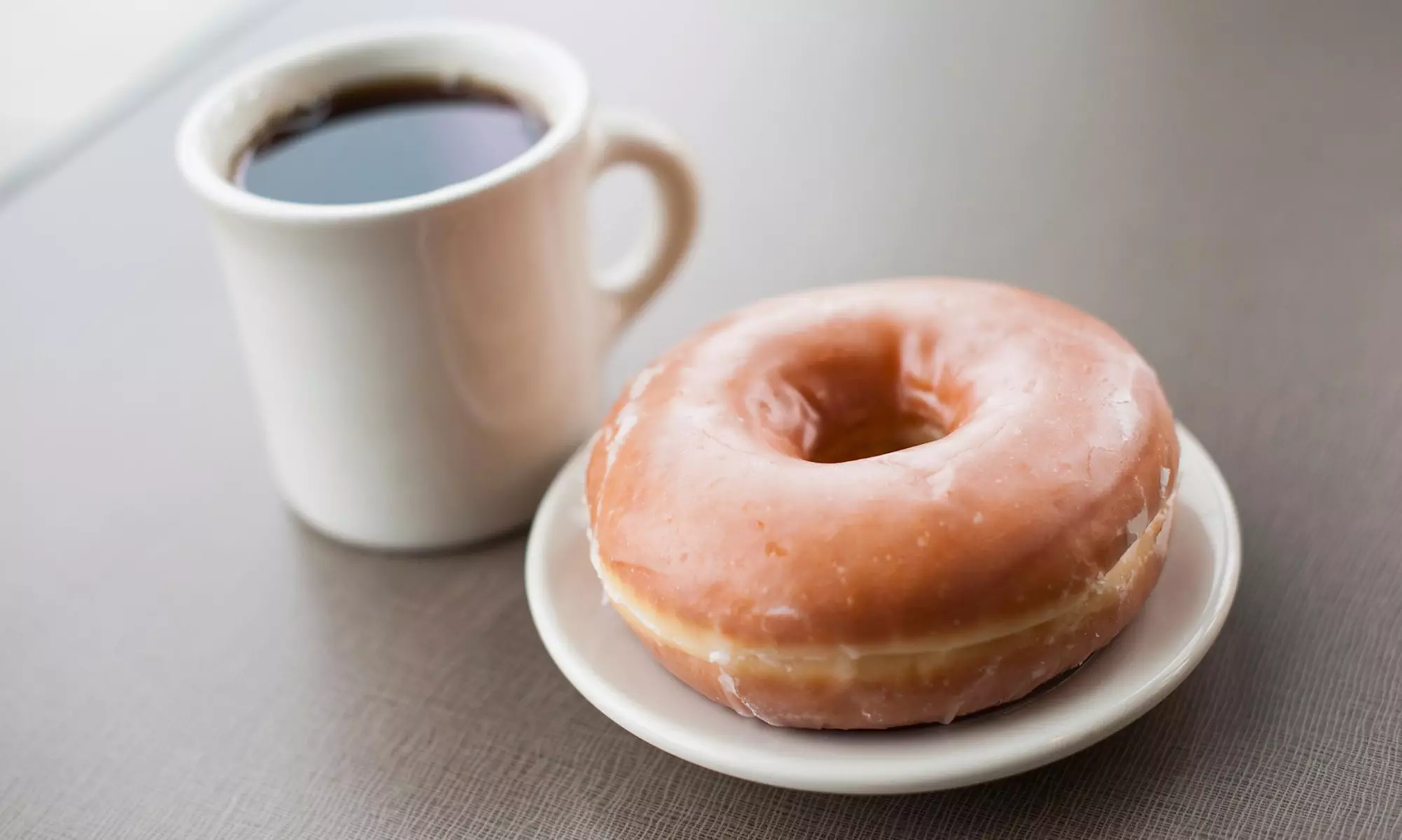 Dozen Glazed Donuts with Option of 2 Sausage Rolls & 4 Large Kona Coffees at Paradise Donuts (Up to 41% Off)  - Primary Image