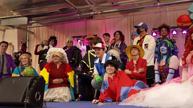 A vibrant anime convention floor with cosplayers and vendor booths.