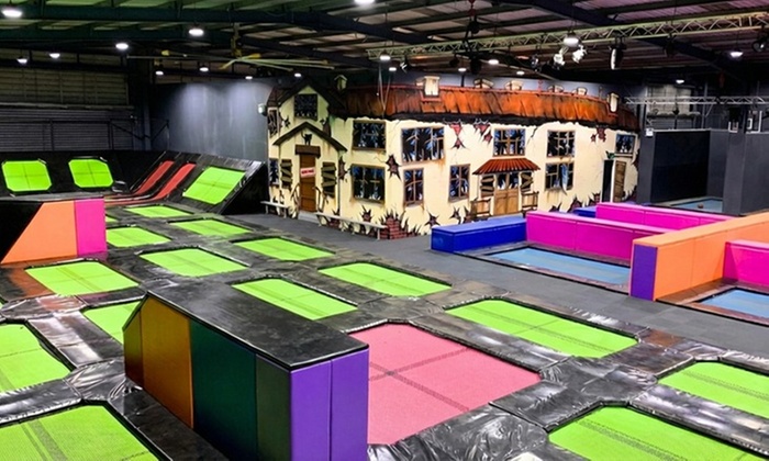 People enjoying various activities in an indoor trampoline park, including jumping on trampolines and engaging in other active fun.