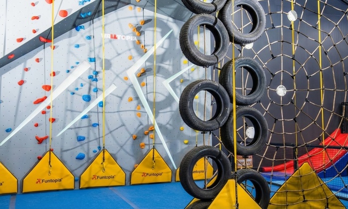 Children playing in a multi-level indoor adventure playground with slides and obstacles