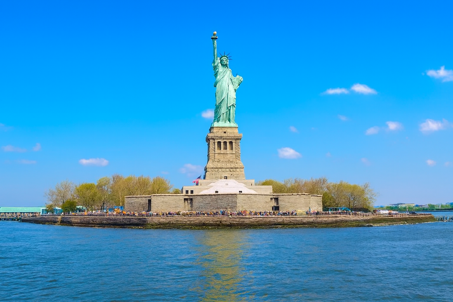 A sightseeing boat passing the Statue of Liberty at dusk