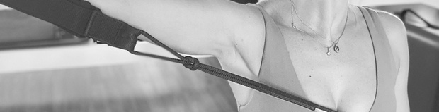 A group of people practicing on Pilates reformer machines in a bright, modern studio.