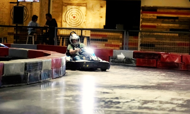 People racing go-karts on an indoor track.