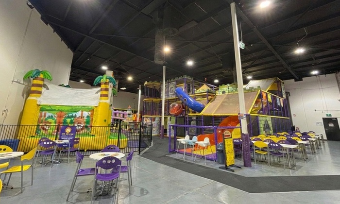Children playing on a colorful inflatable slide and various play equipment in an indoor play centre.