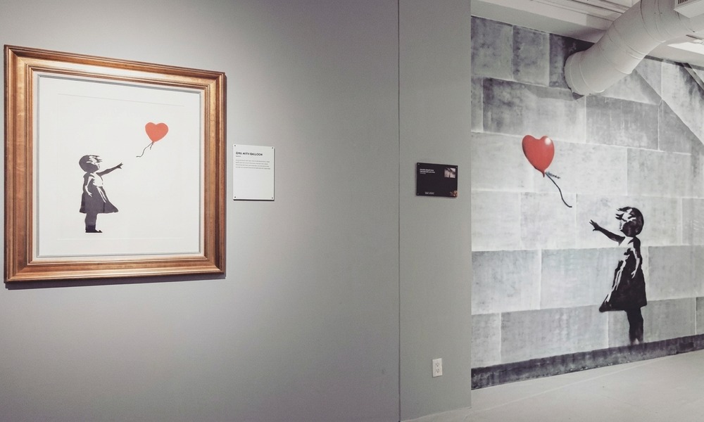Visitors looking at Banksy murals on gallery walls