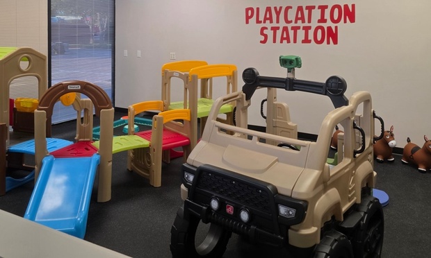 Children playing in a colorful indoor soft play area with slides and climbing structures.