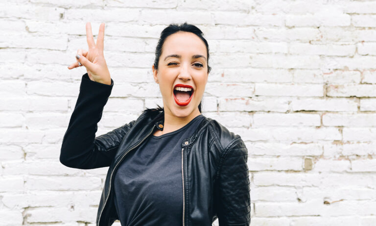 Happy woman with red lipstick smiling and throwing peace sign
