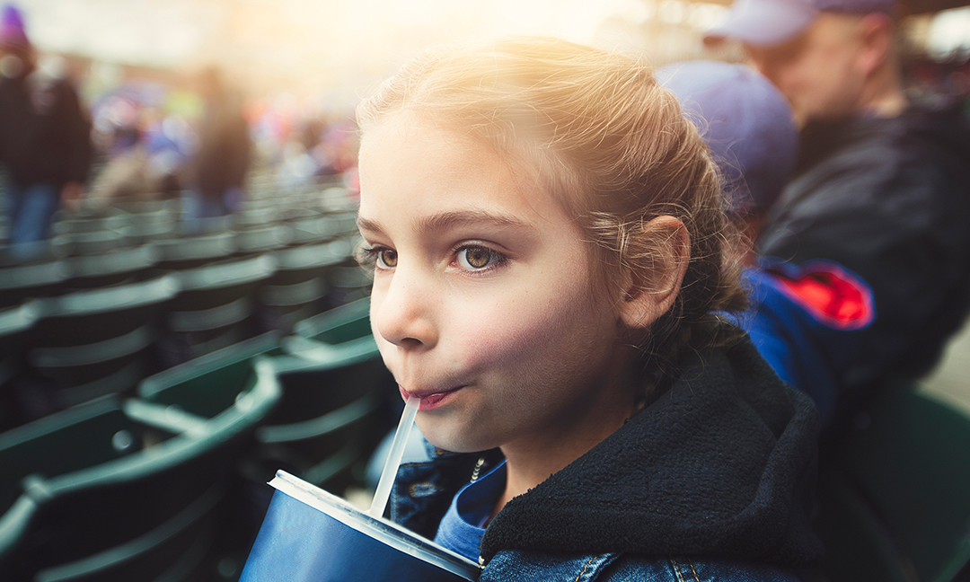 Girl drinking a beverage at a baseball game