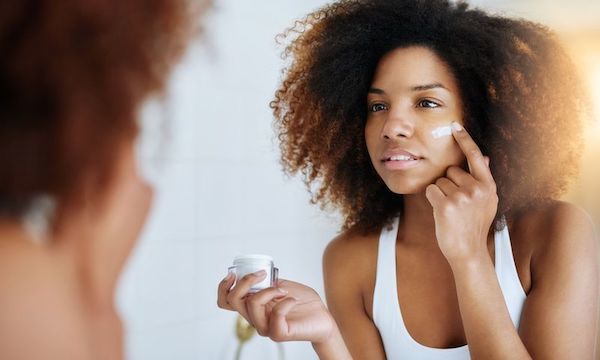 Woman applying moisturizer in the mirror