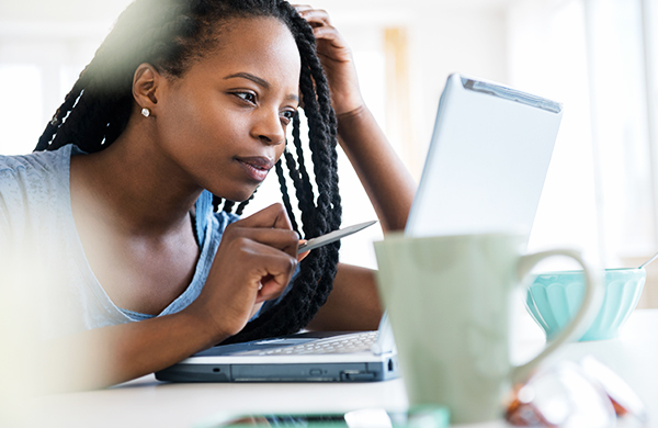 Woman looking thoughtfully at laptop screen