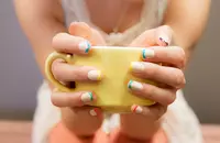 woman with multicolored french mani holding coffee cup