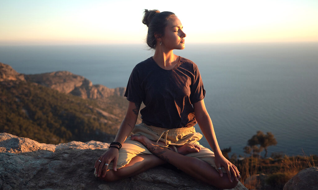 Woman meditating on cliff