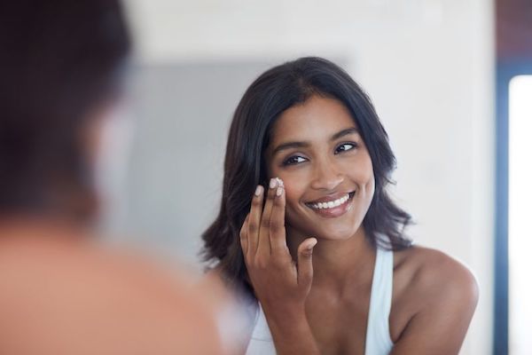 Woman applying skincare product underneath her eyes