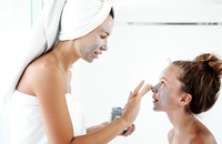 female applying face mask to her younger sister's nose