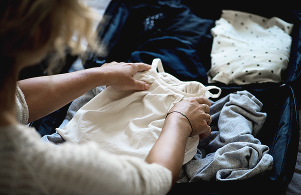 woman packing suitcase with clothing jpg