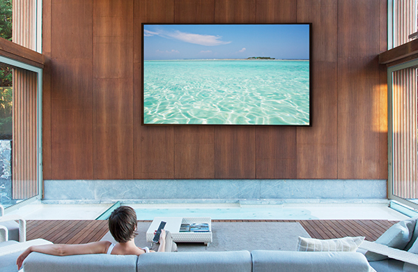woman on living room sofa watching giant wall-mounted flat screen television