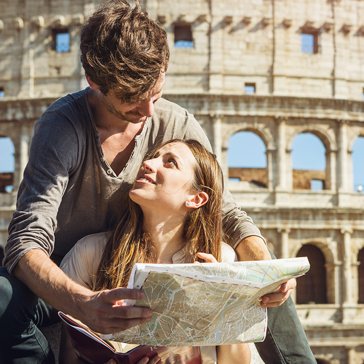tourist couple looking at eachother over a map in Italy.