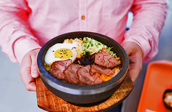 https://img.grouponcdn.com/seocms/HQYt5H6axAEg1zUSiDr1iQvnB6C/hands_holding_bibimbap_on_tray_jpg-600x390