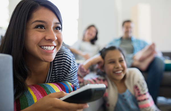 Family with teenage girls watching TV in the living room