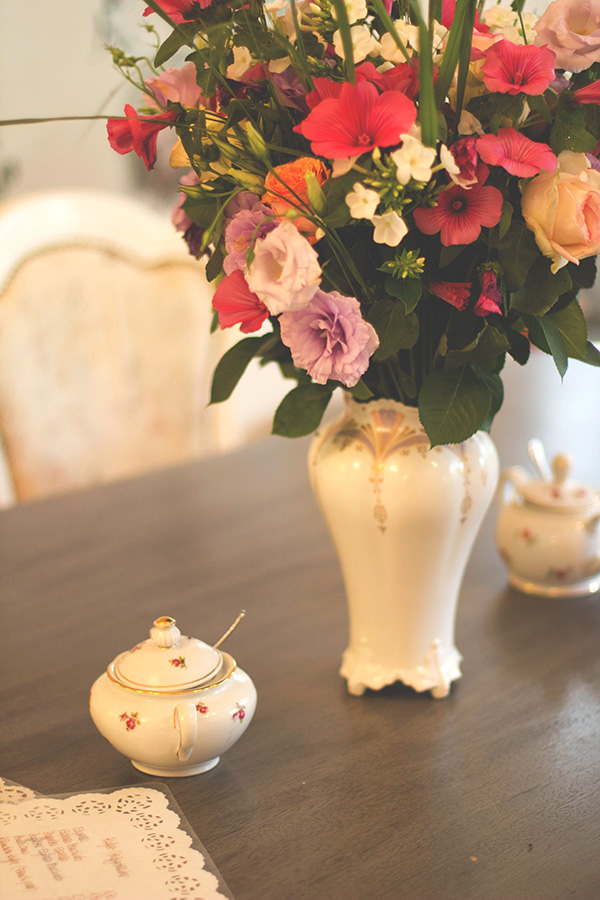 großer Tisch mit frischem Blumenstrauß und altem Geschirr im Café Miss Päpki im belgischen Viertel in Köln