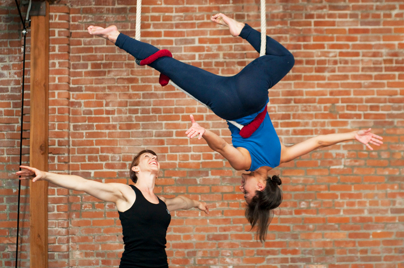 Woman teaching student to do acrobatics with silks