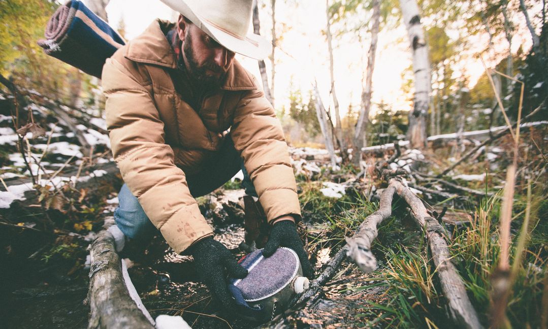 Man filling canteen in the wilderness