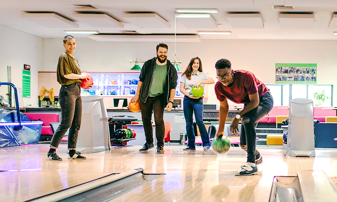 Group of friends showing how to bowl a strike