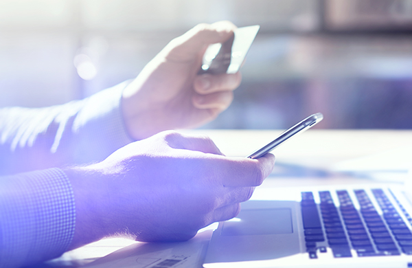 man on phone and laptop paying with credit card