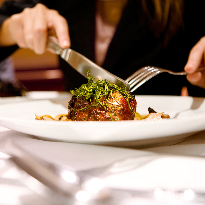 woman cutting into filet mignon steak